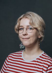 Picture of Emilia Iinatti. I have blonde short hair and red-and white striped shirt. I am smiling at the camera.